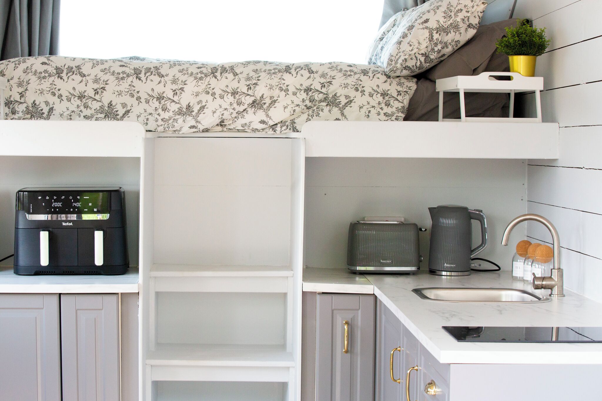Una kitchenette compacta con cafetera, tostadora, hervidor y pileta.