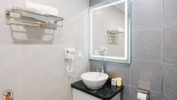 A modern bathroom with a white sink, a glass shower enclosure, and a towel rack.