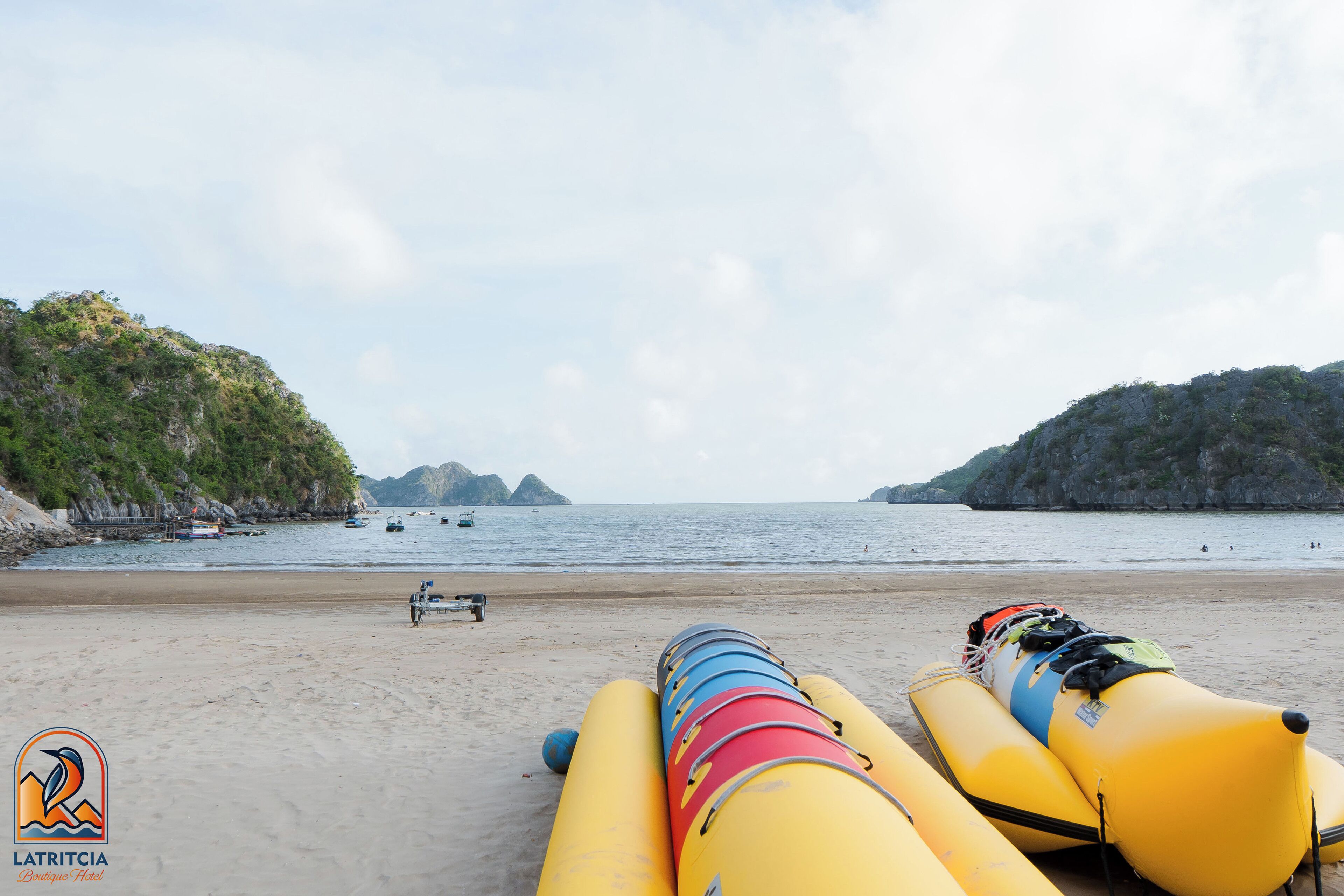 A beach with inflatable rafts and a boat in the water.