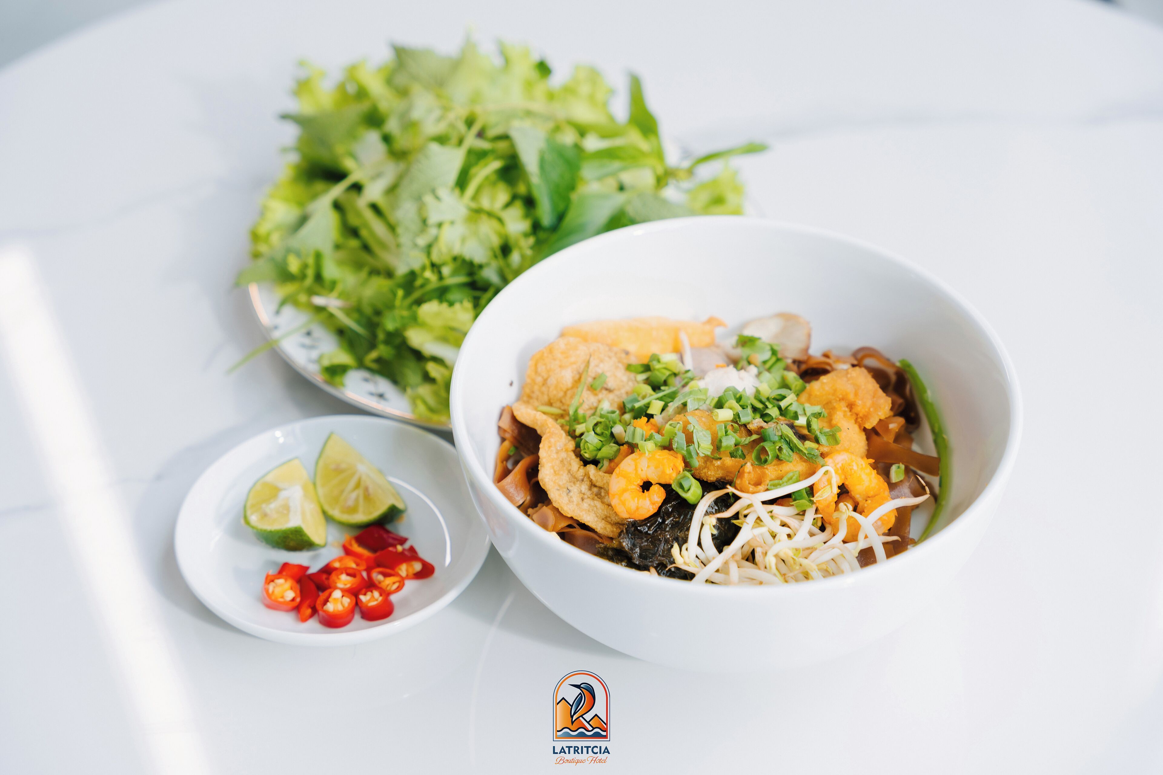 A bowl of food with a side salad and lime wedges.