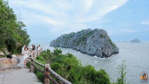 A coastal walkway with a rocky outcrop and a group of people. - Latritcia Boutique Hotel (Hai Phong)
