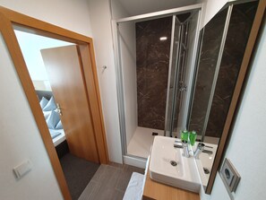 Vierpersoonskamer | Badkamer | Een douche, een haardroger, handdoeken, zeep