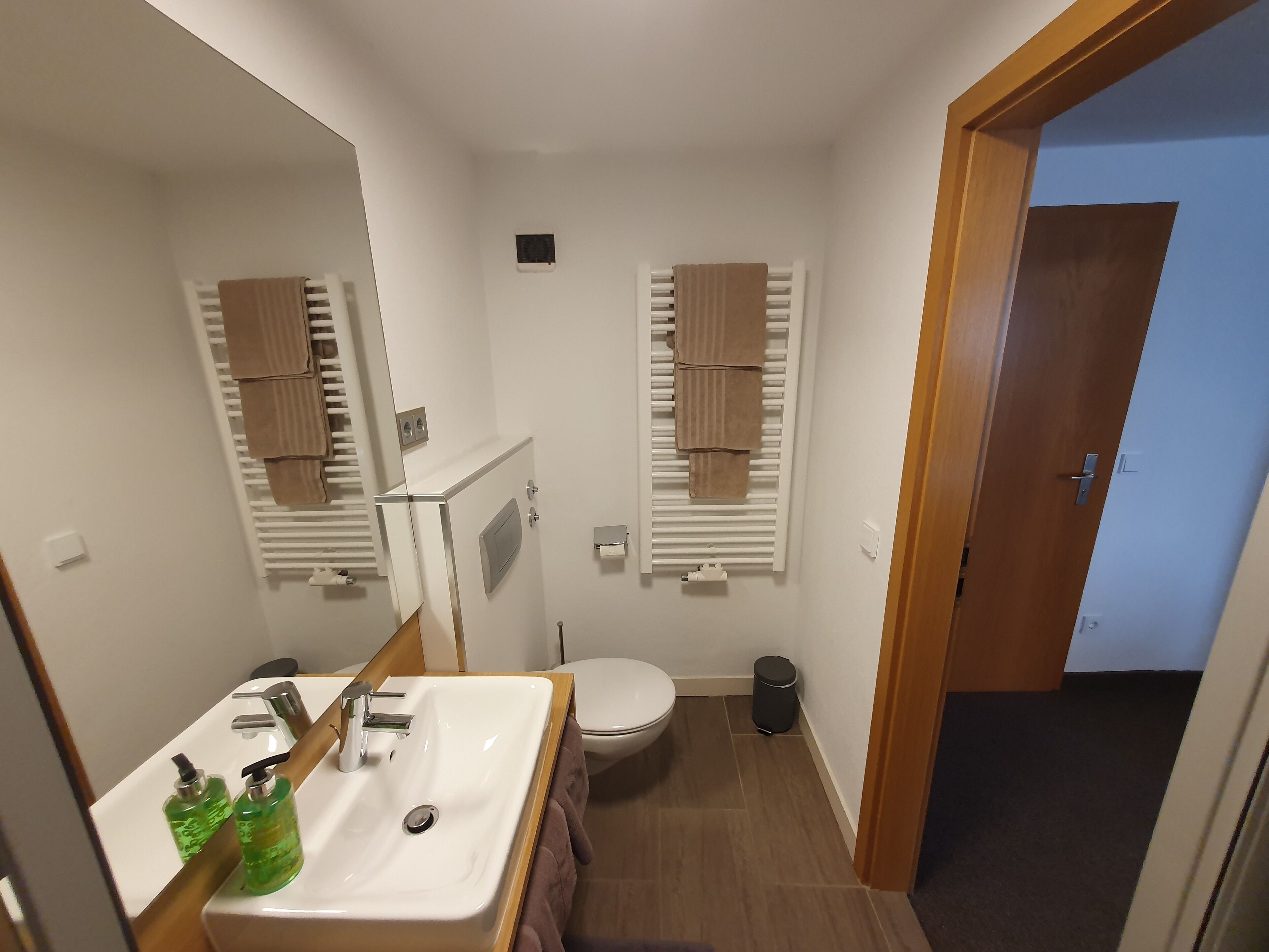 Une petite salle de bain avec un lavabo blanc, un miroir et des porte-serviettes.