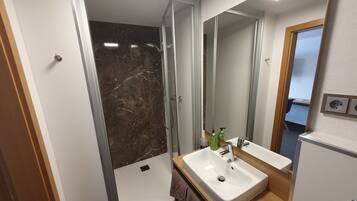 A modern bathroom with a shower, a sink, and a mirror.
