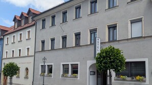 Un bâtiment d’hôtel avec une enseigne indiquant : « HÔTEL, Restaurant, Biergarten ».