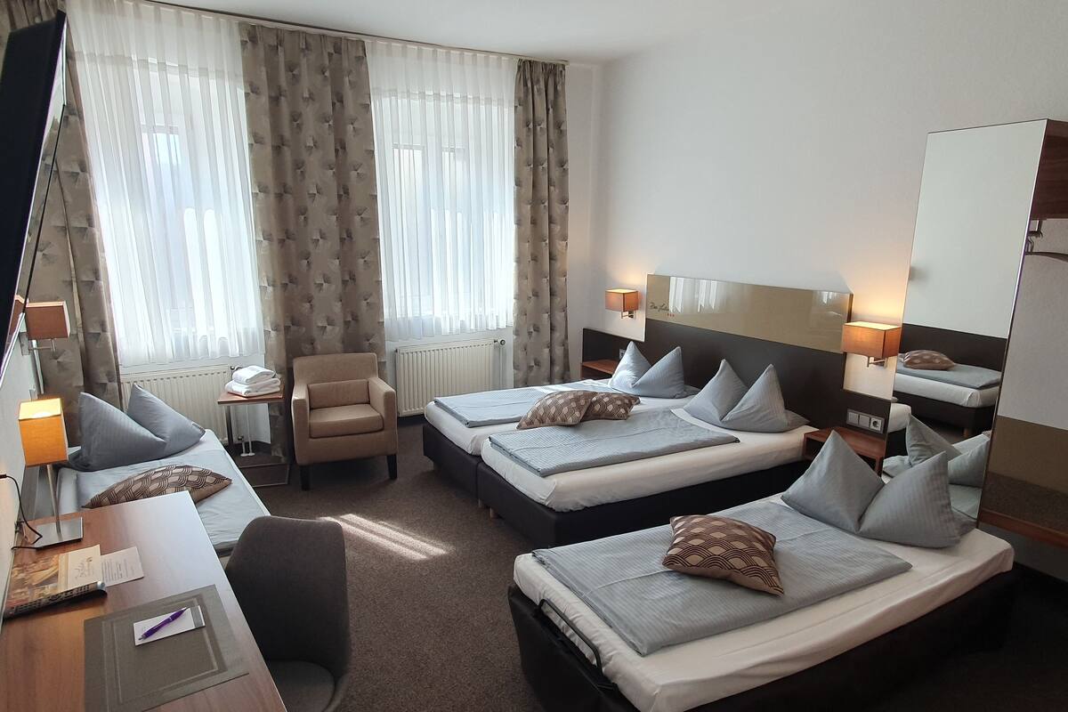 Een hotelkamer met twee bedden, een bureau, een stoel en een televisie.