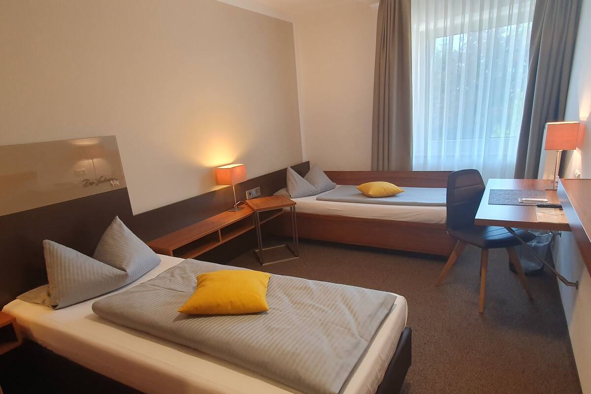 Een hotelkamer met twee bedden, een bureau, een stoel en een lamp.