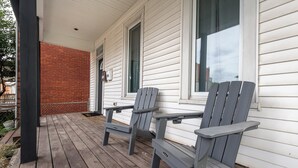 A wooden deck with two Adirondack chairs and a brick wall. - Jackson Street Suites #1 (Dubuque)