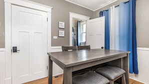 A dining area with a wooden table and chairs, white doors, and blue curtains. - Jackson Street Suites #1 (Dubuque)