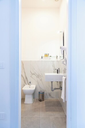 Ein modernes Badezimmer mit einer Bidet-Funktion, einem Waschbecken und einem Fön auf einem Wandregal.