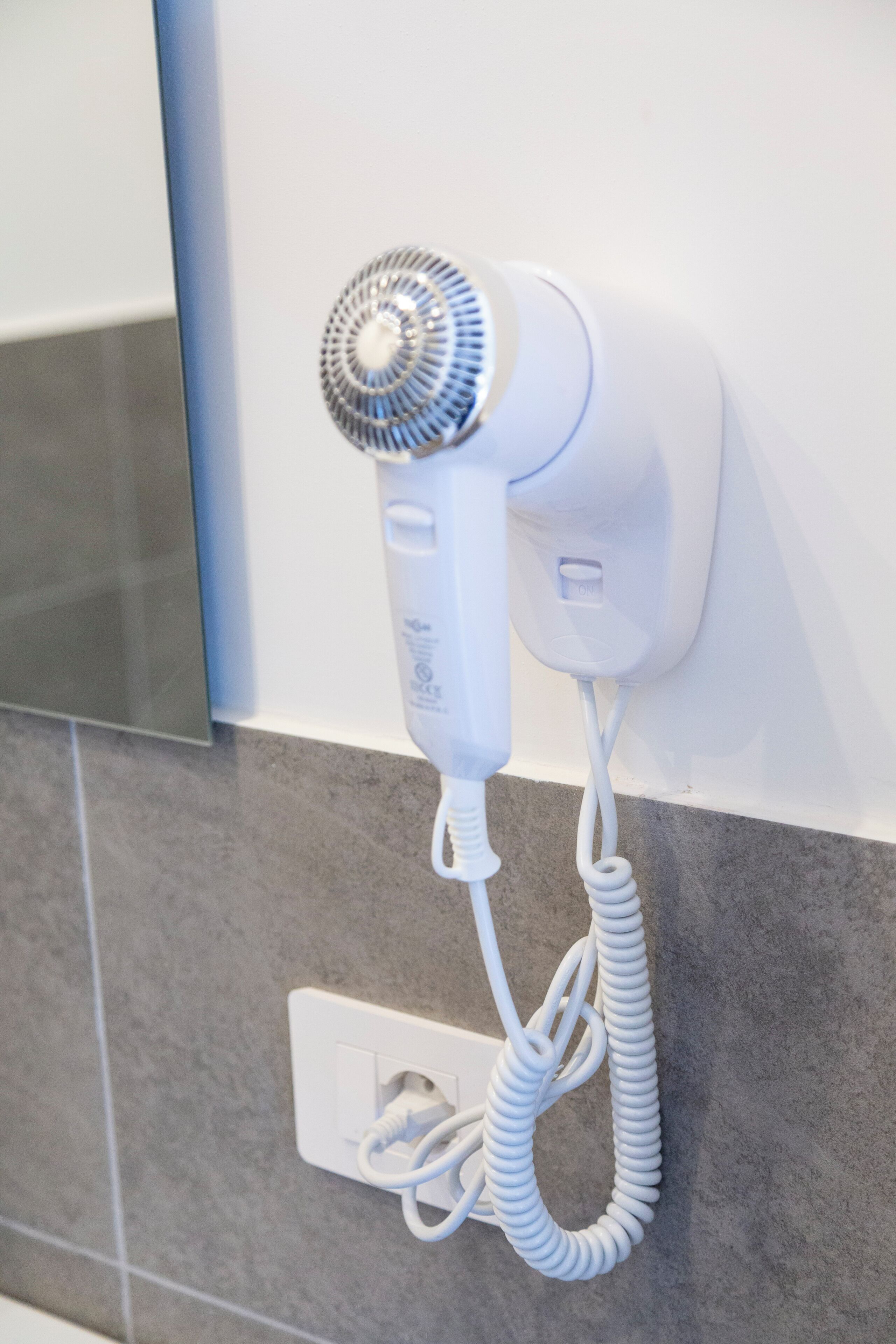 Un secador de pelo montado en la pared con un cable enrollado.