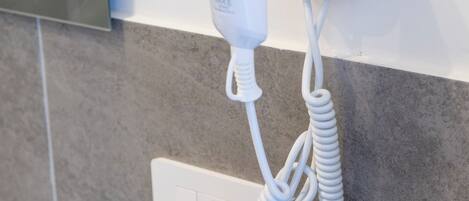 Un secador de pelo montado en la pared con un cable enrollado.