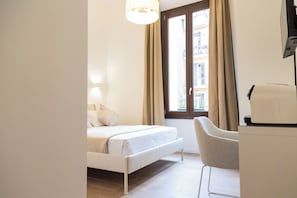 A hotel room with a bed, a chair, a desk, and a window with curtains. - Relais Borsieri (Rome)