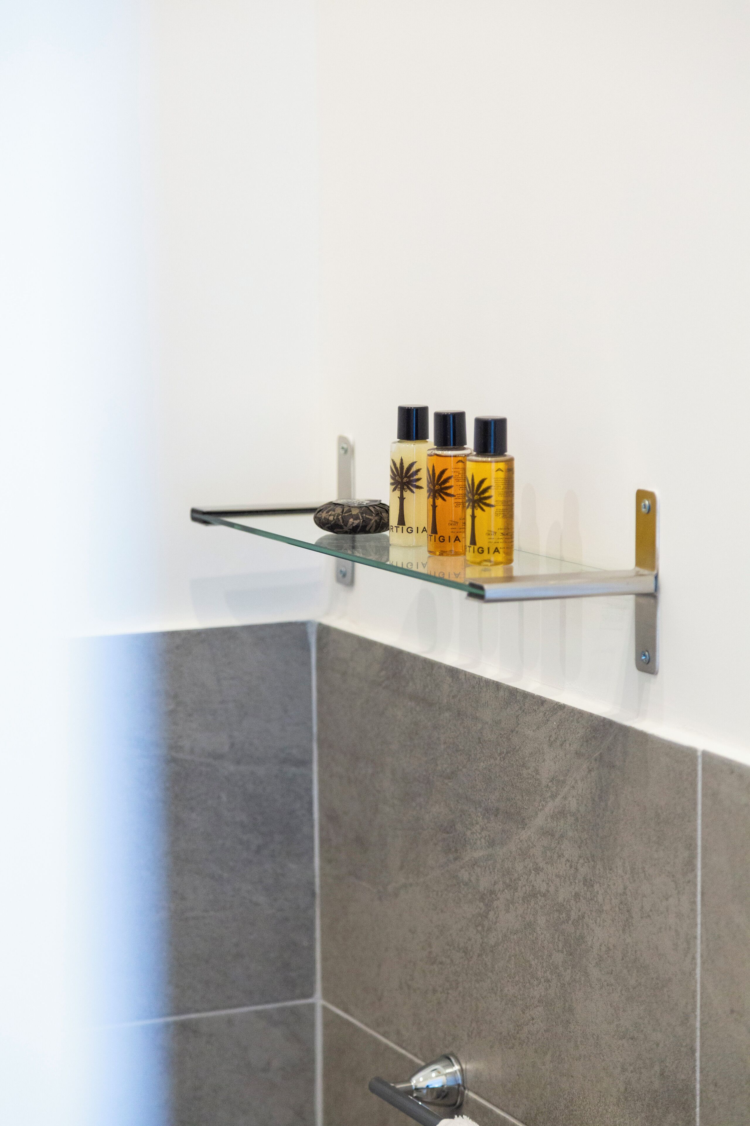 A bathroom with a glass shelf holding toiletries.