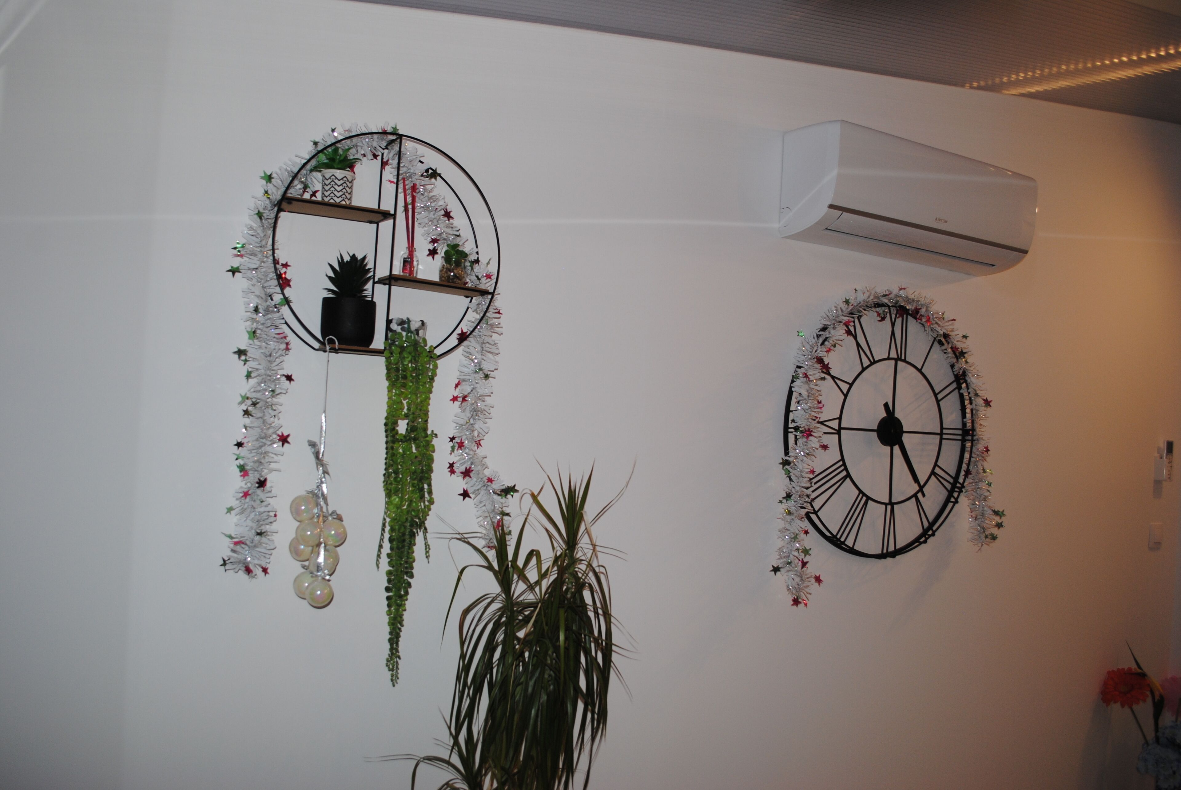 A wall with two decorative clocks and an air conditioning unit.