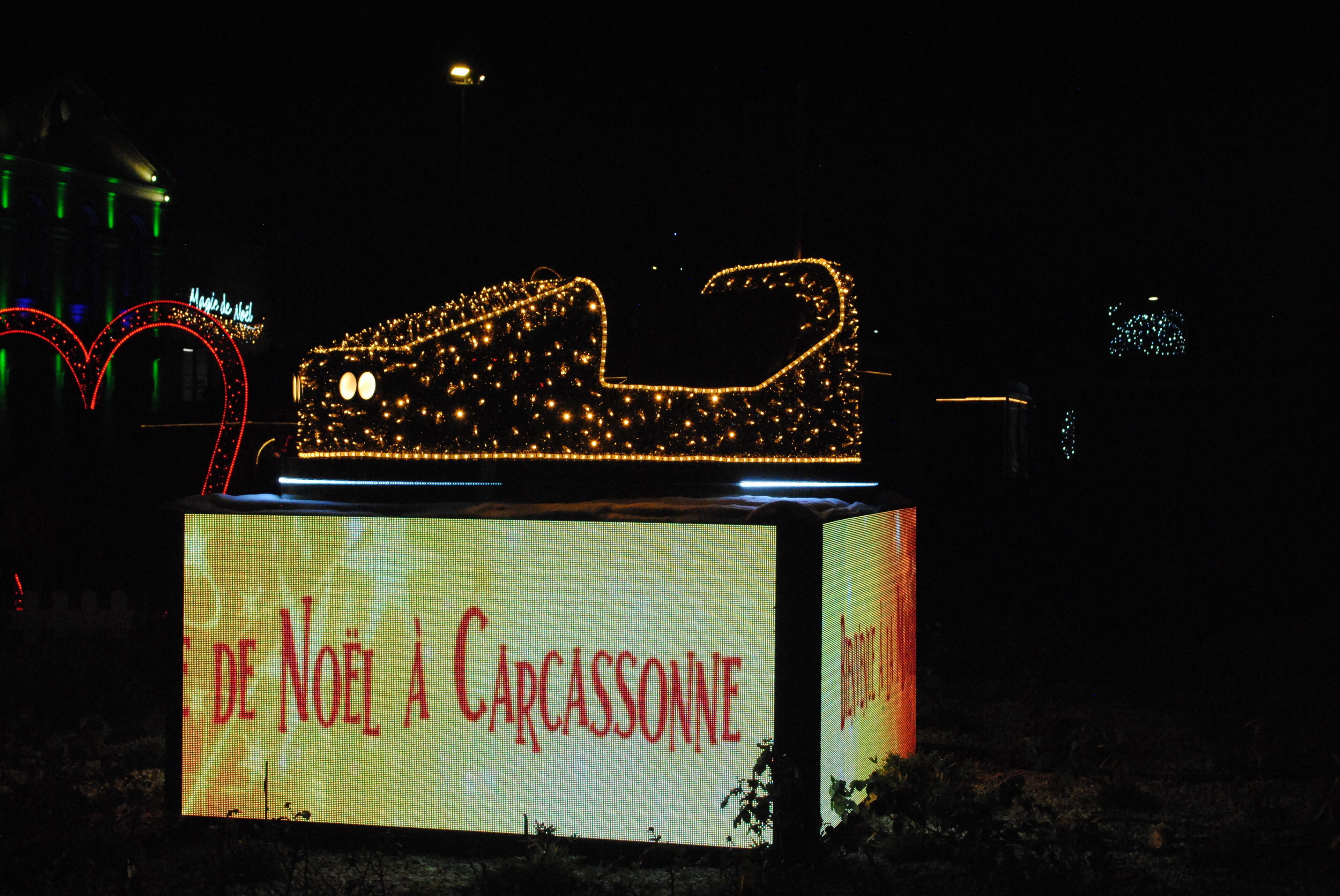 A lit-up Christmas car with a sign that reads "De Noël à Carcassonne."