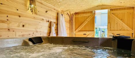 Un spa de madera con hidromasaje, paredes de madera y vistas al exterior.