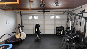 Ein Heimfitnessraum mit Laufband, Ergometer und Krafttrainingsgeräten.