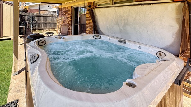 Ein Whirlpool mit Holzterrasse und Backsteinmauer im Hintergrund.