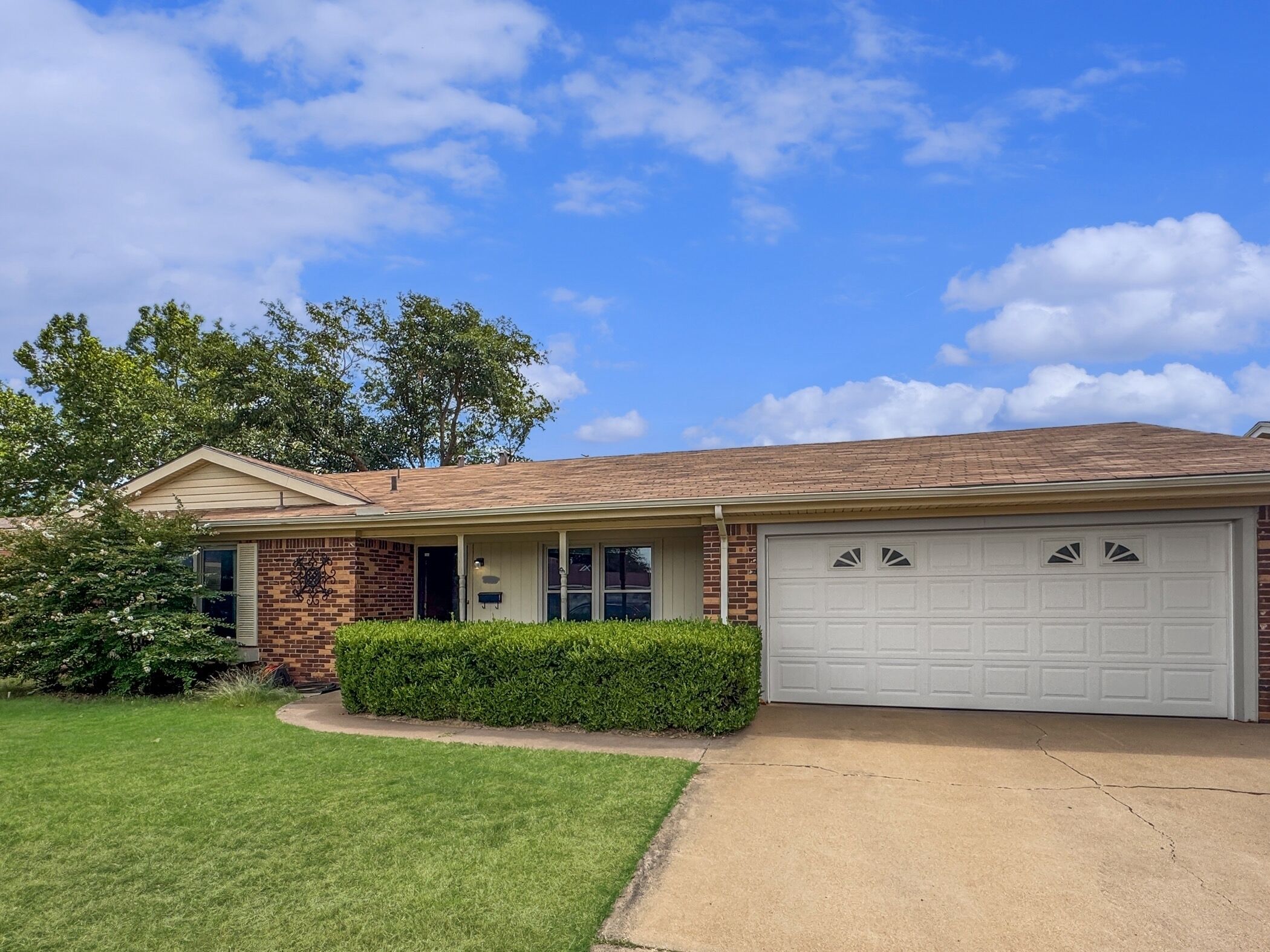 Una casa de dos plantas con fachada de ladrillo, un porche cubierto y un garaje.