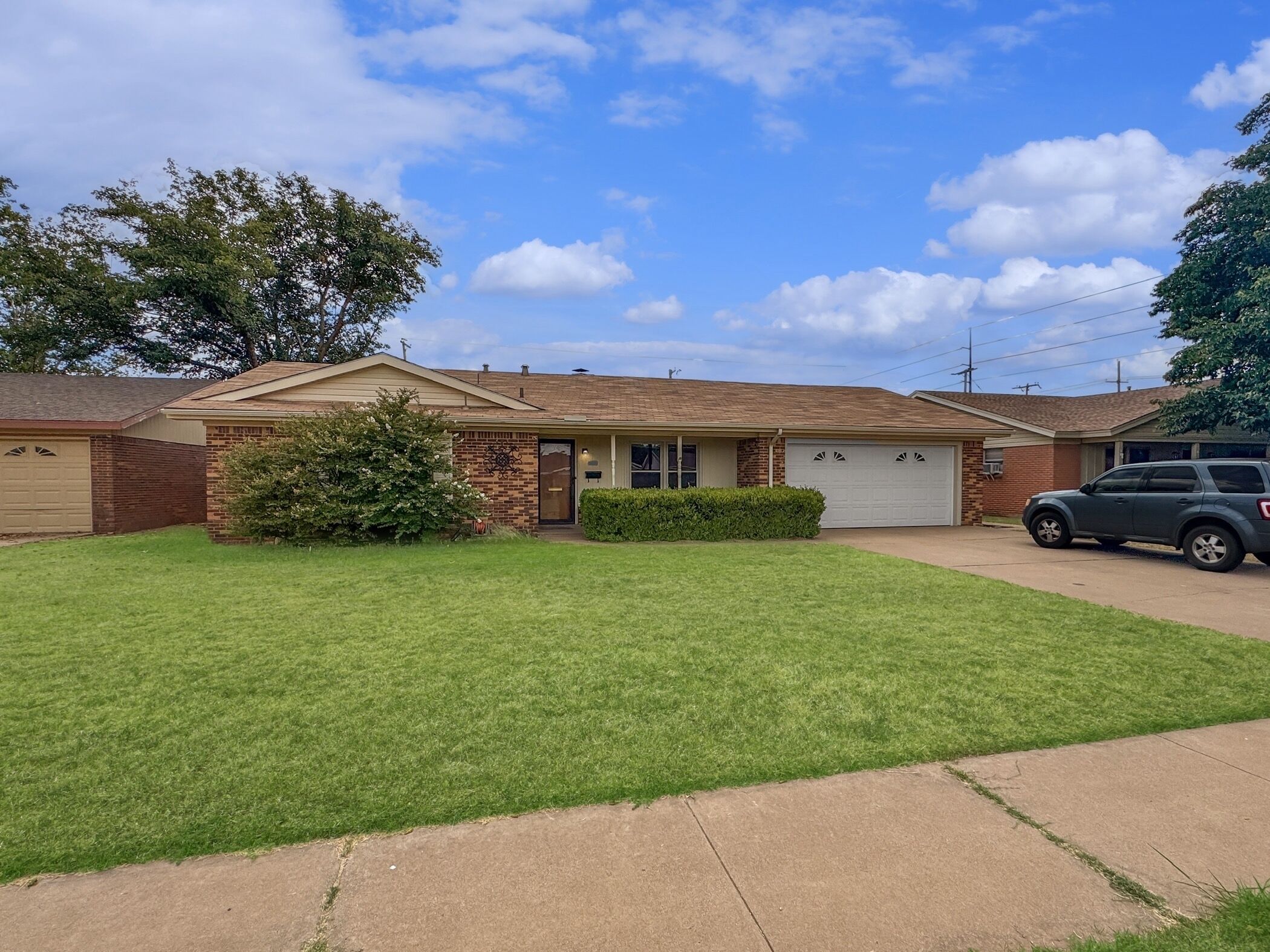 A single-story house with a brick facade, a front garage, and a well-maintained lawn.