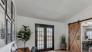 Un coin repas avec une table en bois, des chaises, une plante en pot et une porte coulissante de style grange.