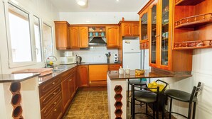 Una cocina con armarios de madera, una isla integrada con taburetes de bar, un refrigerador y una ventana.