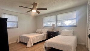 A bedroom with two single beds, a ceiling fan, and two windows with blinds. - Sunny 2BR Retreat · Enclosed Patio · Pet Friendly · Near Gulf Beaches (Port Richey)