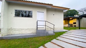 Una casa moderna con fachada blanca, puerta principal y un pequeño porche con mobiliario exterior.