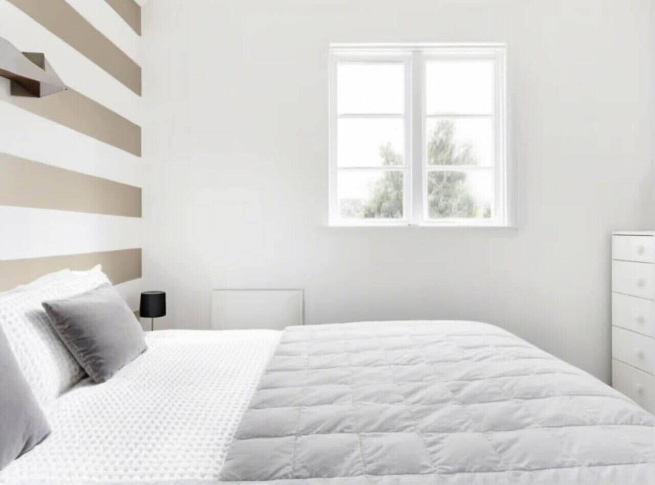 A bedroom with a bed, a nightstand, a dresser, and a window with a view of trees.