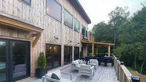 A wooden deck with outdoor seating, large windows, and a pergola. - Stunning views, Luxurious, Peaceful, dog friendly, king beds,fire pit,WIFI,AC,EV (Townshend)