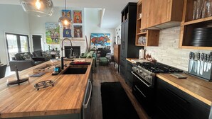 A modern kitchen with a wooden island, black appliances, and a dining area with a sofa and chairs. - Stunning views, Luxurious, Peaceful, dog friendly, king beds,fire pit,WIFI,AC,EV (Townshend)