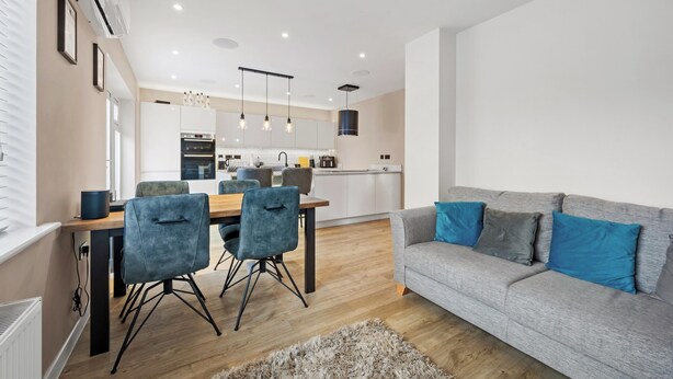 Un salon moderne avec un canapé gris, des fauteuils bleus et une table à manger en bois.