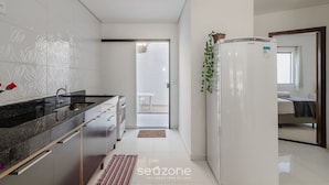 A modern kitchen with a black countertop, white tiles, and a refrigerator.