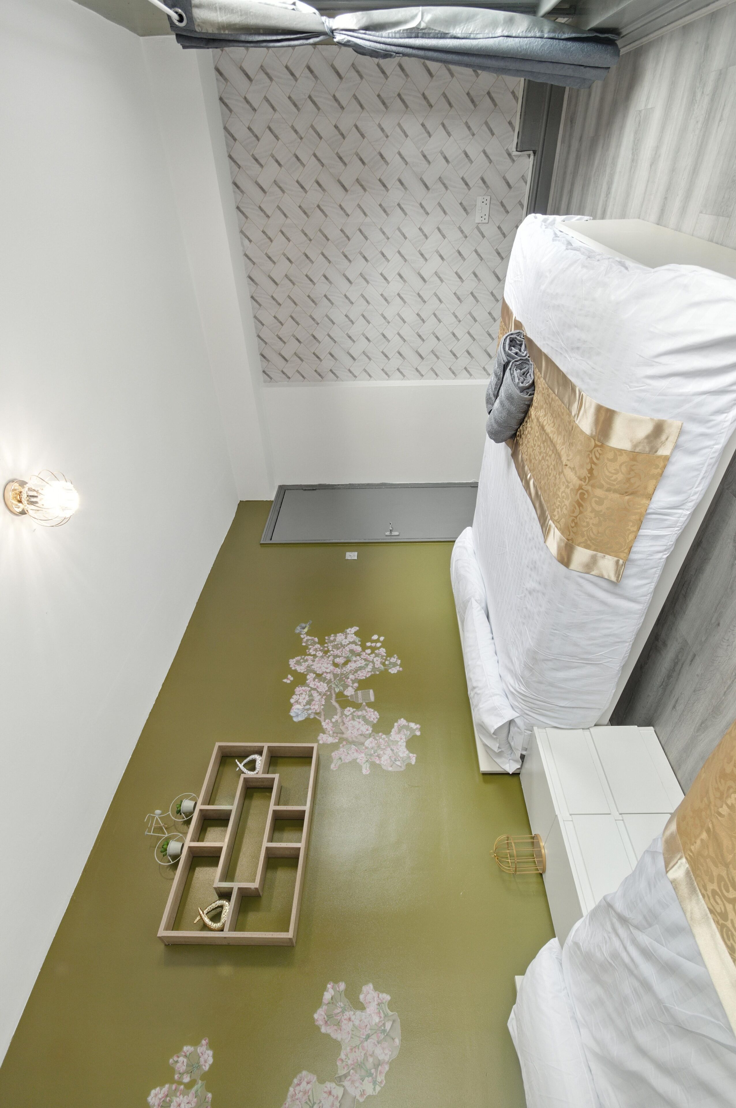 Habitación de hotel con cama, una mesita, luz empotrada en la pared y un panel decorativo.