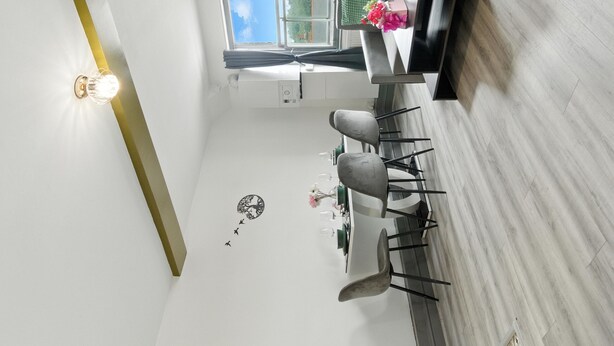 A compact kitchen with a dining area, a clock, and a window with curtains.