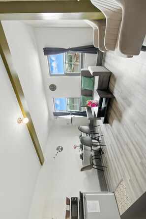A compact kitchen with a dining area, a clock, and a window with curtains. - Brick Lane Hideout-Walking distance to Towerbridge (London)