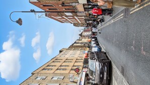 A street view with a row of shops, including a bridal shop, and a parked car.