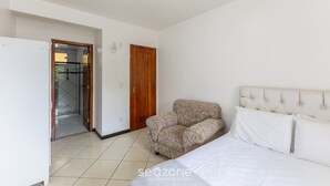 Een slaapkamer met een bed, een bank, een houten deur en een betegelde vloer.