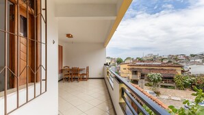 Een balkon met een eettafel en stoelen, een uitzicht op de stadsgezicht en een balustrade.