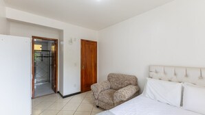 Een slaapkamer met een bed, een bank, een houten deur en een betegelde vloer.