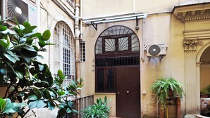 A courtyard with a brick floor, a brown gate, and various potted plants. - Nicole Suite (Rome)