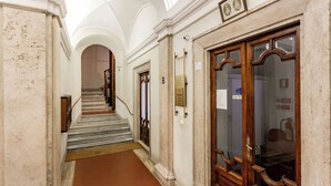 A hallway with marble walls, a wooden door, and a staircase leading to an upper floor. - Nicole Suite (Rome)