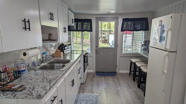 Eine kleine Küche mit weißen Schränken, einer Marmorarbeitsplatte, einer Spüle und einem Kühlschrank.