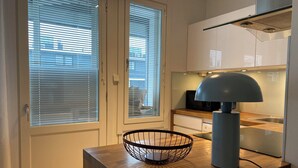 Een moderne keuken met een houten aanrecht, een zwarte draadmanden, een blauwe lamp en een roestvrijstalen spoelbak.