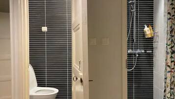 A bathroom with a toilet, a shower with a handheld showerhead, and a towel rack.