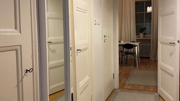 A hallway with white doors, a dining area with a table and chairs, and a window with curtains. - Homely 1BR in Lively Area with Strategic Location (Helsinki)