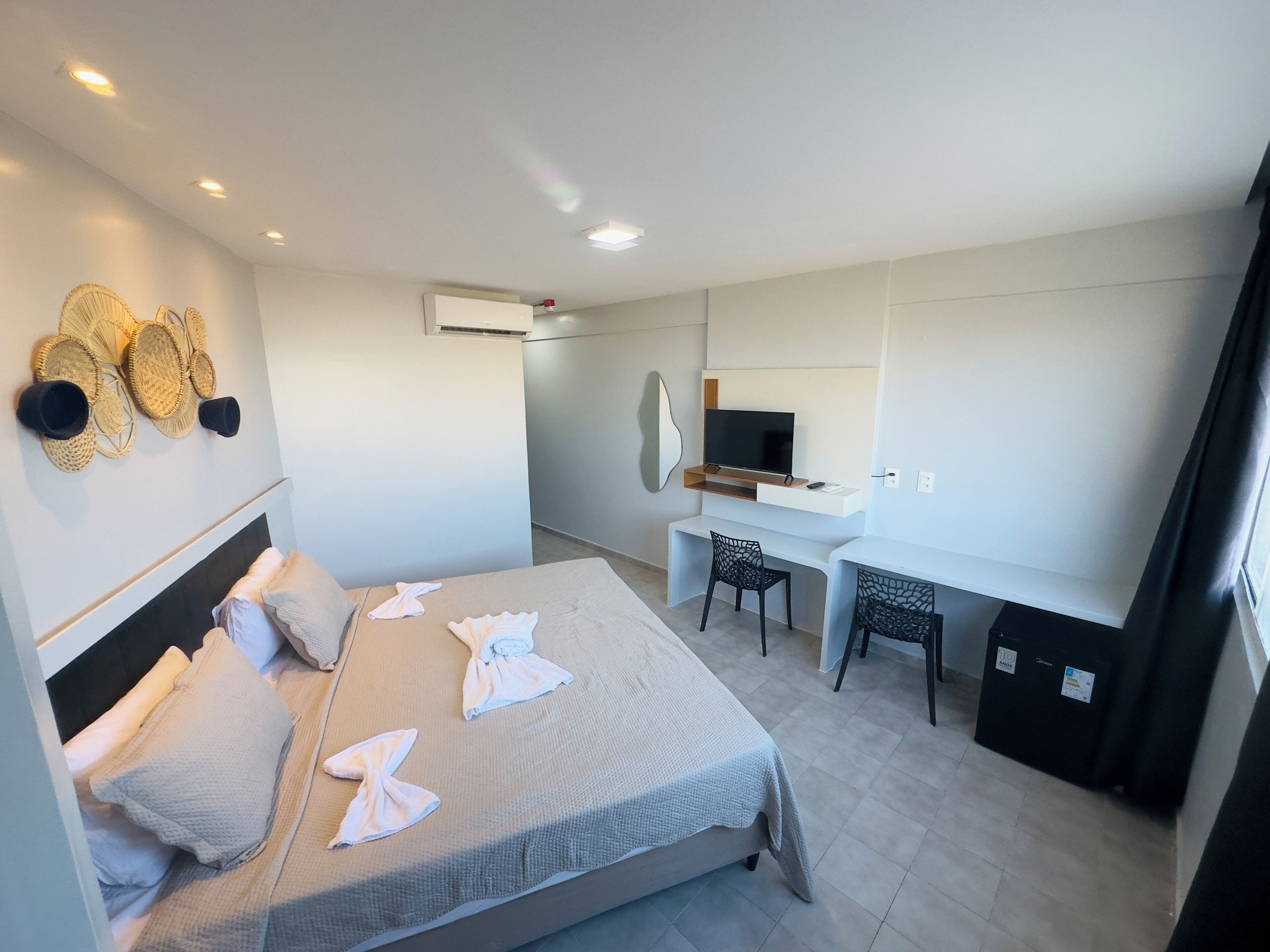 A hotel room with a bed, desk, and TV.