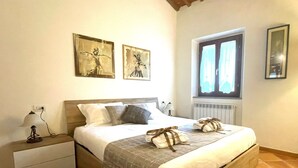 Ein Schlafzimmer mit Bett, Nachttisch und einem Fenster mit Vorhängen.