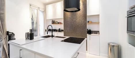 A modern kitchen with a central island, white cabinetry, and a black range hood.